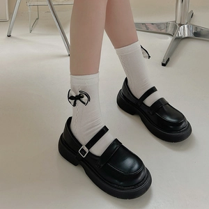 Close-up of black platform Mary Jane shoes with double straps and white bow socks