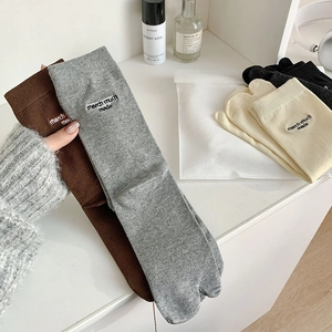 Detail of embroidered letters on cotton ribbed tabi flip-flop socks in earth tones