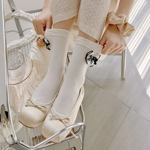 Detail of white lace socks with black bow and cream satin square toe flats for women