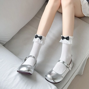 Détail de chaussettes Lolita en résille blanche avec dentelle et nœud noir sur chaussures