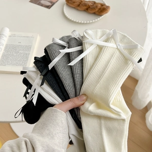 Detailed close-up of ribbed cotton socks in white, grey, and black with satin bows