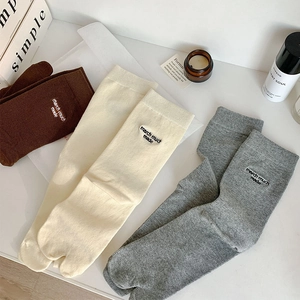 Detail view of Tabi split-toe socks in brown and white with minimalist embroidery
