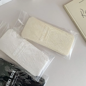 Vue détaillée des chaussettes montantes en dentelle fleurie en noir, blanc et beige