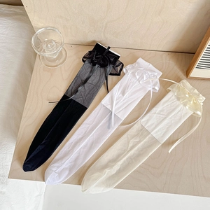 Chaussettes hautes style JK avec dentelle et nœuds en noir, blanc et beige sur bois