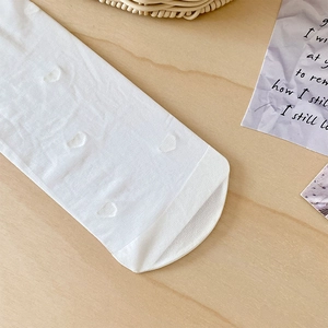 Detail of white lace calf socks featuring heart jacquard patterns and reinforced toes