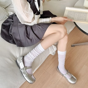 Detailed close-up of white mesh knee-high socks paired with silver star Mary Jane shoes