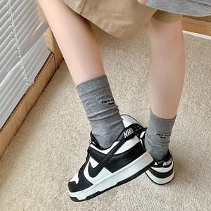 Trendy black and white low-top sneakers paired with grey ribbed letter knit crew socks