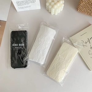 Détail de chaussettes en dentelle au crochet en blanc, noir et beige avec motifs floraux