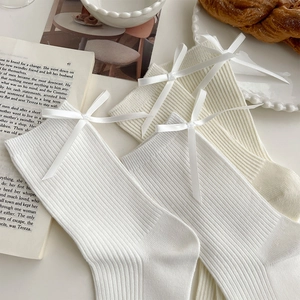 Detail of white ribbed crew socks with satin bow accents on vintage French background