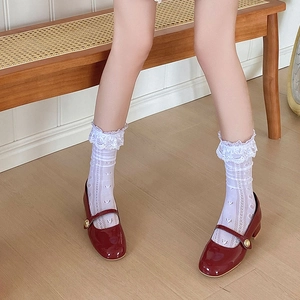 Vue détaillée des babies en cuir verni rouge avec boucle dorée et chaussettes en dentelle