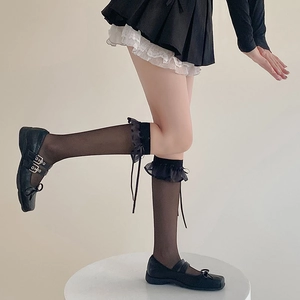 Détail de chaussettes mi-bas noires transparentes avec dentelle et nœud en ruban doux