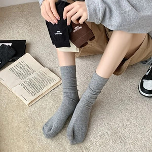 Close-up of ribbed split-toe socks with letter embroidery on the cuff in neutral tones