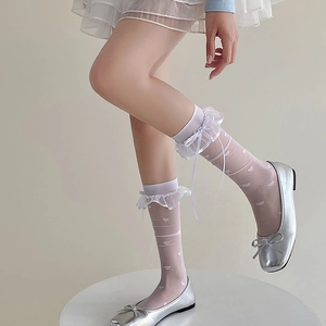 Detailed view of white lace ruffles and bow on sheer heart pattern calf socks