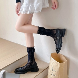 Détail de chaussettes noires en dentelle à motifs de cœurs et chaussures Mary Jane
