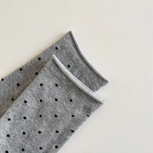 Detailaufnahme grauer Baumwollsocken mit schwarzen Punkten und modischem Rollrand