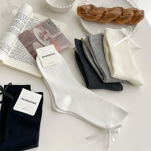 Detailed view of combed cotton socks with side bow tie decoration in various colors