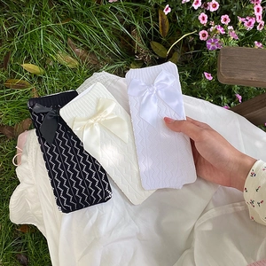 Close-up of knit wave texture socks with large satin bows in black, cream, and white