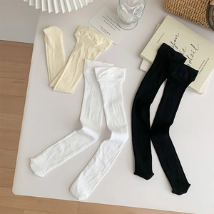 Detail of mesh texture and ribbed cuffs on white, beige and black calf-high socks