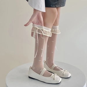 Detail of white lace knee-high socks with heart pattern and elegant ribbon bows