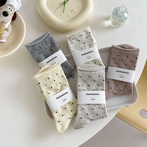 Fünf Paar gepunktete Damensocken in Pastellfarben, ordentlich präsentiert im Tablett