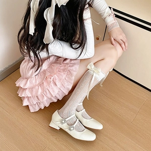 Detail of white lace mid-calf socks with bow accents and white Mary Jane shoes