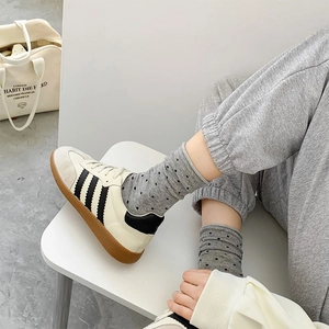 Detailansicht grauer Punktesocken kombiniert mit cremefarbenen Turnschuhen