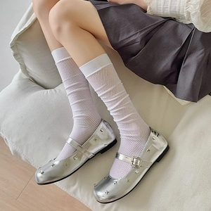 Detail of white mesh knee-high socks paired with silver metallic Mary Jane flats