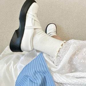 Gros plan de chaussettes à froufrous blancs avec des chaussures Mary Jane vernies et une jupe