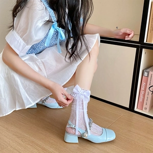 Close-up of light blue patent leather Mary Jane shoes with pearls and lace bow socks