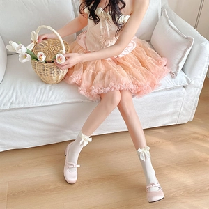 Detail shot of pink satin Mary Janes with white bow socks in a Japanese Lolita style