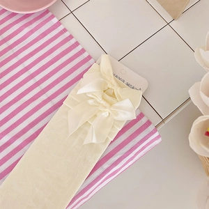 Close-up of beige Lolita style mid-calf socks featuring delicate satin bow decorations