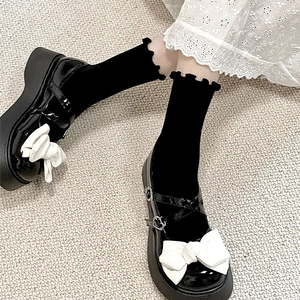 Détail de chaussures Mary Janes en cuir verni noir avec nœud blanc et chaussettes