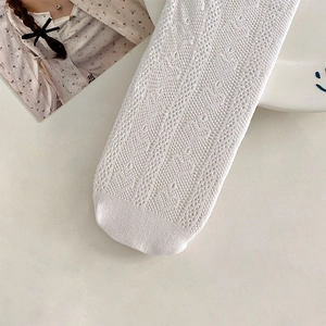 Detailed view of white lace heart patterned socks with delicate hollow knit texture