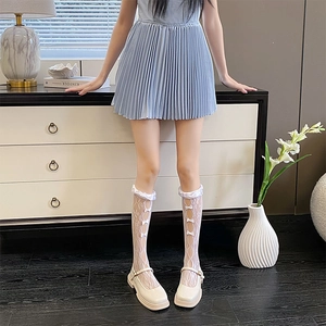 Close-up of white lace calf socks with bow details paired with Mary Jane shoes
