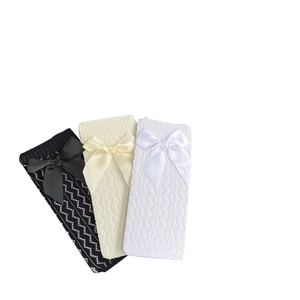 Three pairs of bow-knot mid-calf socks in black, beige, and white with wavy knit pattern
