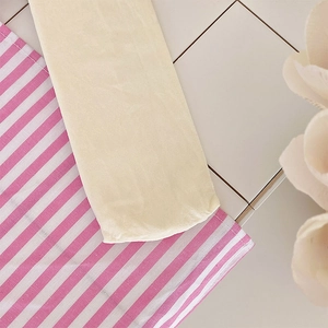 Detailed texture of beige Lolita style bow socks on a pink striped fabric background