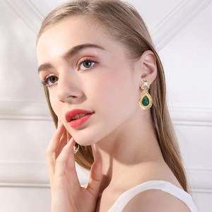 Close-up of vintage drop earrings with green and purple crystals worn by a model