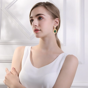 Detailed view of vintage emerald drop earrings with purple gemstones on a model