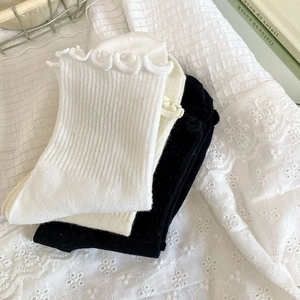 Détail de chaussettes à volants en blanc, beige et noir avec texture en maille côtelée