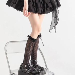 Détail de chaussettes hautes Lolita en dentelle noire avec nœuds en satin et volants