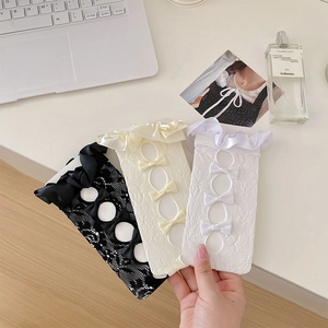 Close-up of lace knee high socks with delicate bow ties in black, cream, and white colors