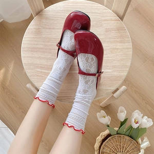 Dettaglio di calze in pizzo bianco con bordi rossi e scarpe Mary Jane rosse