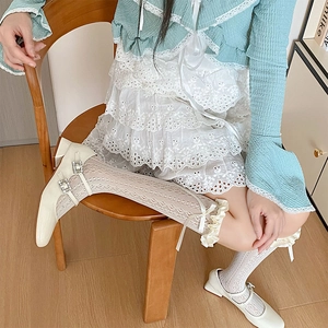 Détail de chaussures Mary Jane crème avec boucles strass et chaussettes en dentelle
