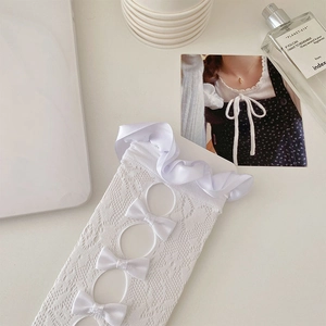 Detail of white lace calf socks with satin ruffles and elegant bow accents
