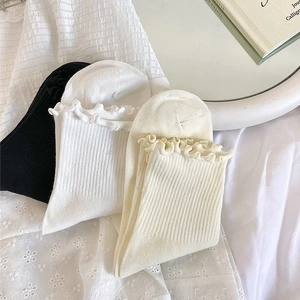 Gros plan de trois paires de chaussettes à volants de style japonais en noir, blanc et beige