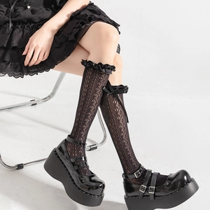 Détail de chaussettes hautes en dentelle noire avec bords plissés et nœuds en ruban