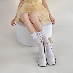 Detail of white Lolita socks with satin bows and pearl charms paired with Mary Janes