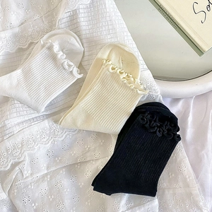 Vue détaillée des chaussettes à bordures volantées en blanc, beige et noir en coton