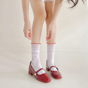 Dettaglio di scarpe Mary Jane rosse con calze in pizzo bianco e bordo arricciato rosso