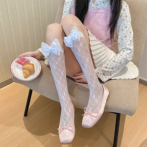 Close-up of white lace knee-high socks with satin bows and pink velvet ballet flats